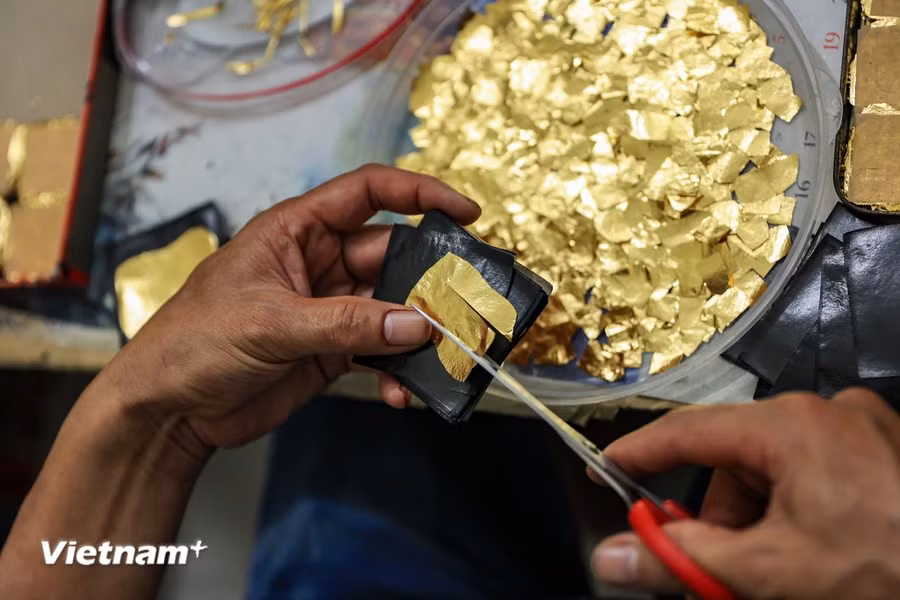 Cutting the gold leaves is one of the steps involved in the process of rolling gold and silver. (Photo: Vietnam+)