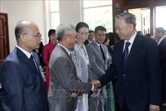 State President To Lam (R) meets Vietnamese Embassy staff and representatives of the Vietnamese community in Laos (Photo: VNA)