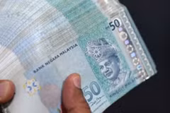 A money changer counts Malaysian ringgit banknotes for customers in Kuala Lumpur. (Photo: AFP)