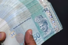 A money changer counts Malaysian ringgit banknotes for customers in Kuala Lumpur. (Photo: AFP)