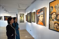 A staff of Thang Long Art Gallery staff introduces artworks to a visitor at the exhibition. (Photo: VNA)