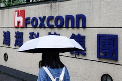 A woman carrying an umbrella walks past the logo of Foxconn outside a company's building in Taipei, Taiwan, Oct. 31, 2022. (Photo: Reuters)
