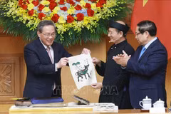 Vietnamese Prime Minister Pham Minh Chinh (R) and Chinese Premier Li Qiang got hands-on experience of making a Dong Ho folk painting. (Photo: VNA)