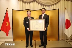 Hoang Binh Quan (left), former member of the Party Central Committee and former Chairman of its Commission for External Relations, receives the “Order of the Rising Sun, Gold and Silver Star” from Japanese Ambassador Ito Naoki on December 15. (Source: VNA)