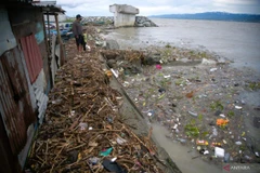A father and son watch waste sweeping up to the shore near Palu Bay, Central Sulawesi, Indonesia. (Photo: antaranews.com)