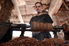 An artisan shapes the outside of a wood log. (Photo: VNA) 