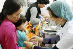 A vaccine shot is given to children. (Photo: VNA)