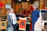 International visitors experience the traditional new year calligraphy activity (Photo: VNA)