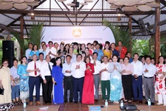 A representative of the Vietnam Fatherland Front Committee of Ho Chi Minh City poses for a commemorative photo with Vietnamese adoptive parents and Lao and Cambodian students. (Photo: VNA)