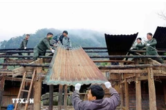 Police officers and soldiers of Lai Chau province join hands with local residents to eliminate temporary and dilapidated houses in the locality. (Photo: VNA)