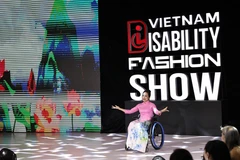 A model with physical challenge confidently showcase ao dai (Vietnamese traditional long dress) on the fashion runway. (Photo: VNA)