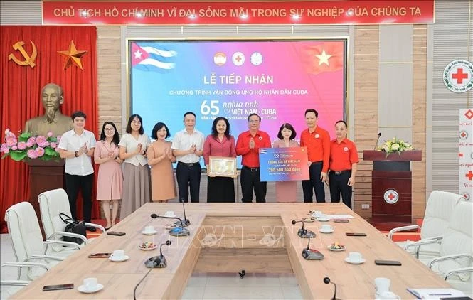 Deputy General Director of the Viet Nam News Agency Nguyen Thi Su (fifth, from right) presents donations to the Cuban people to the Viet Nam Red Cross Society. (Photo: VNA)