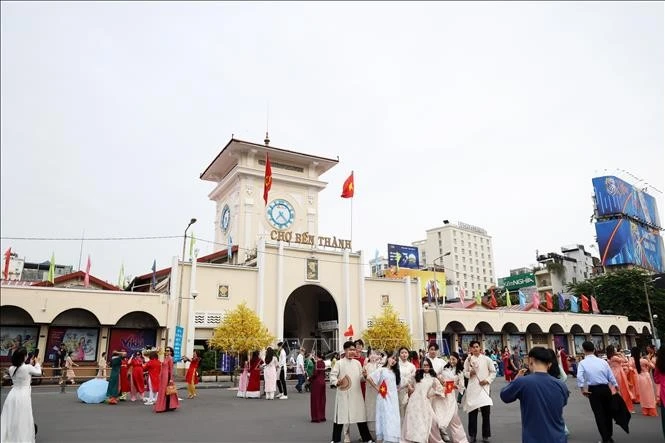 Tourists pose for photos in front of Ben Thanh Market, Ho Chi Minh City. (Photo: VNA)