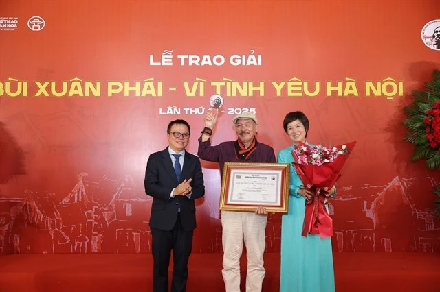 Le Quoc Minh (left), Chairman of the Viet Nam Journalists’ Association and Editor-in-Chief of Nhan dan Newspaper and Vu Viet Trang (right), General Director of the Viet Nam News Agency, present the Grand Prize to musician Tran Tien. (Photo: VNA)