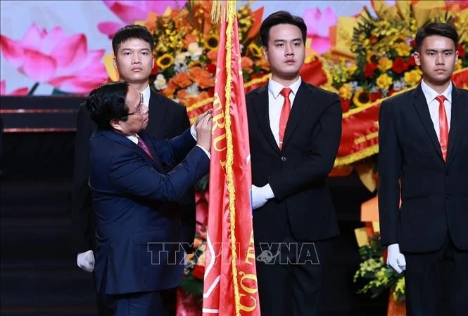 Prime Minister Pham Minh Chinh attaches the Ho Chi Minh Order on the VOV's traditional flag (Photo: VNA)