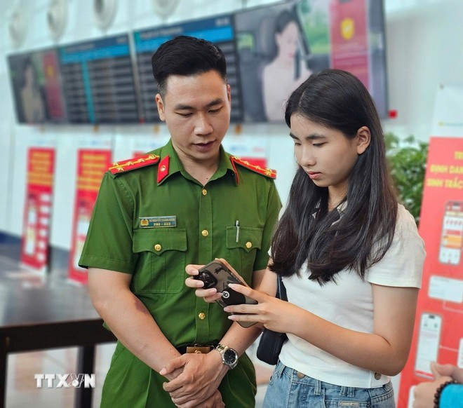 A police officer guides passenger process online check-in via VNeID application. (Photo: VNA) biometric-checkin-2.jpg