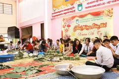 Teachers and students at the Nguyen Du Lao-Vietnamese bilingual language school in Vientiane make "chung" cakes. (Photo: VNA)