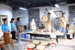 Visitors watch a traditional pottery-making demonstration at Bat Trang craft village. (Photo: hanoimoi.vn)