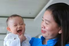 A child accompanies her mother to receive a certificate of merit honouring exemplary families with two daughters, at a ceremony organised in then Hau Giang province on January 5, 2023. (Photo: VNA) 