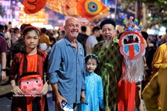 An international tourist joins the Mid-Autumn Festival atmosphere by Hoan Kiem Lake, surrounded by colourful traditional toys. (Photo: VNA)