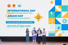 Deputy Minister of Agriculture and Environment Nguyen Hoang Hiep and Pauline Tamesis, UN Resident Coordinator in Vietnam present flowers to welcome WHO and IOM as new members of the disaster risk reduction partnership. (Photo: VNA) 
