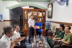 Ngo Thanh Phuc (L), Chairman of the Long Hai People’s Committee, presents a national flag to a local ship owner. (Photo: VNA)