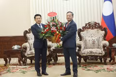 Vietnamese Ambassador to Laos Nguyen Minh Tam (R) hands over flowers from Prime Minister Le Minh Hung to congratulate Lao PM Saleumxay Kommasith. (Photo: VNA)
