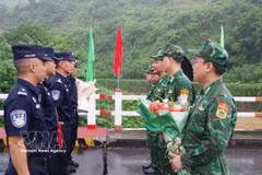 Commanders of the Vietnamese and Chinese patrol teams exchange flowers at the demarcation line on the Vietnam-China border friendship bridge (Photo: VNA) 