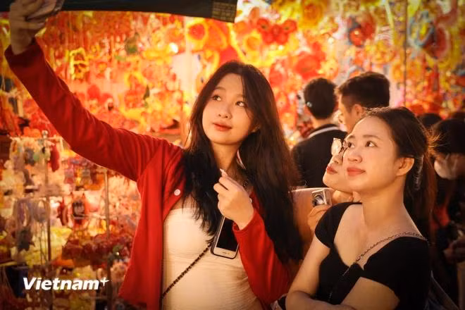 Young people take the opportunity to take photos and check-in on the colourful street. (Photo: VietnamPlus)