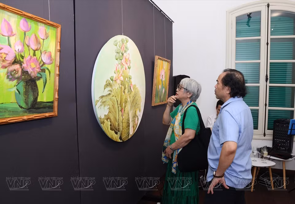 Visitors admire the lotus paintings. (Photo: VNP/VNA)