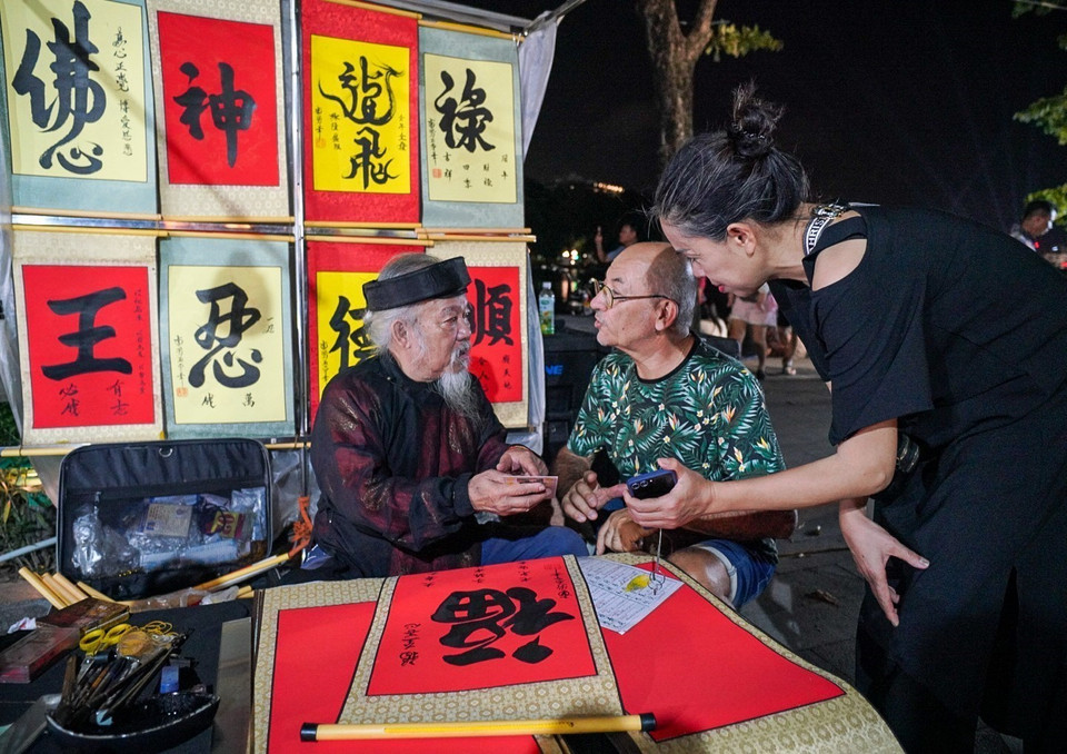 Foreign tourists request calligraphy at Hoan Kiem Lake's pedestrian street. (Photo: VNA)
