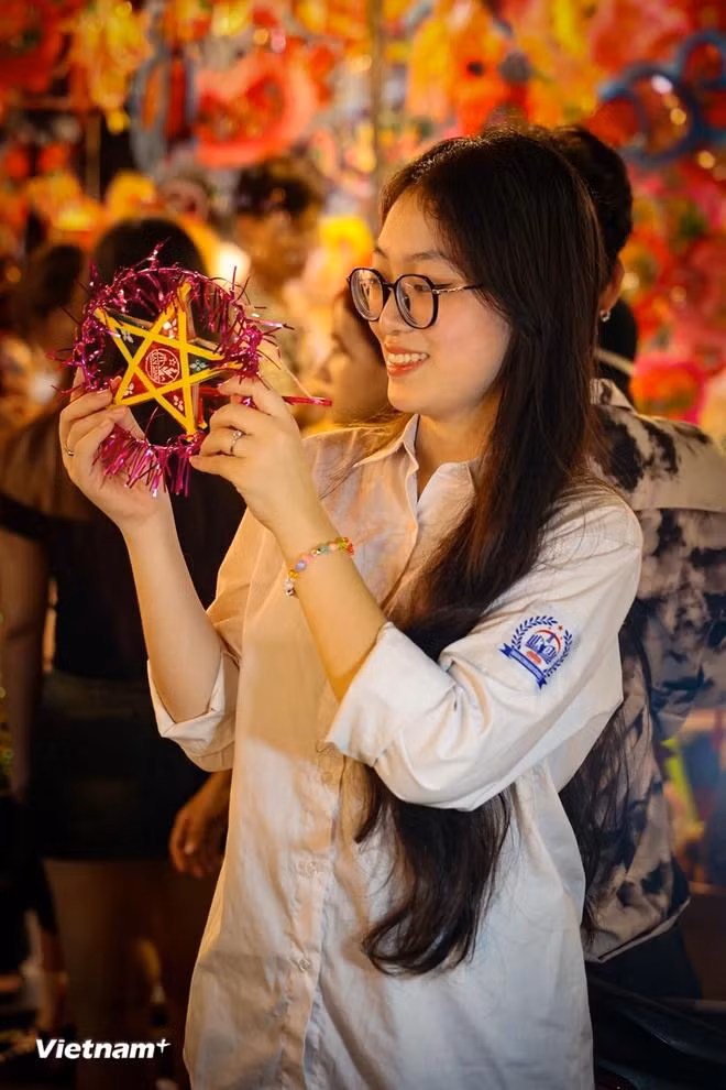 Minh Trang, a Hanoi girl, buys herself a mini star-shaped lantern to take souvenir photos. She shared that although these traditional toys are inexpensive, they still capture the essence of the Mid-Autumn Festival. "Just having one makes you feel the festive atmosphere of the season," she said. (Photo: VietnamPlus)