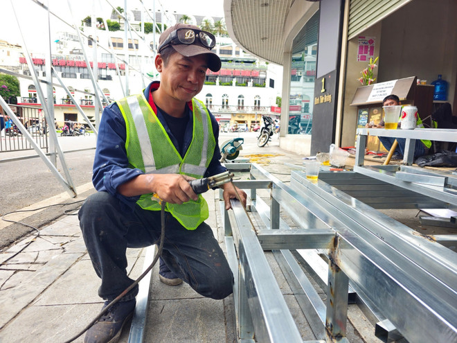 A worker installs a barrier outside the "Shark Jaw" building. (Photo: VNA) vna-potal-ha-noi-bat-dau-thao-do-di-chuyen-cac-trang-thiet-bi-va-ha-giai-cong-trinh-toa-nha-ham-ca-map-8053546.jpg
