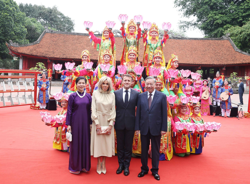 Party General Secretary To Lam and his spouse, together with French President Emmanuel Macron and his spouse, pose with artists performing royal court music at the Temple of Literature. (Photo: VNA)