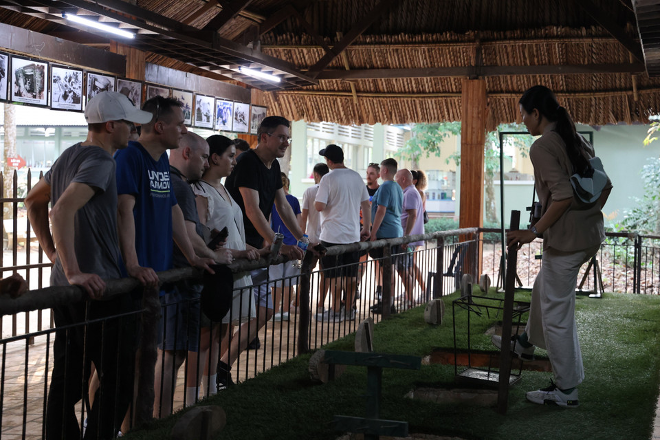 Foreign tourists listen to a guide explaining the role of spike pits in combat. (Photo: VNA)