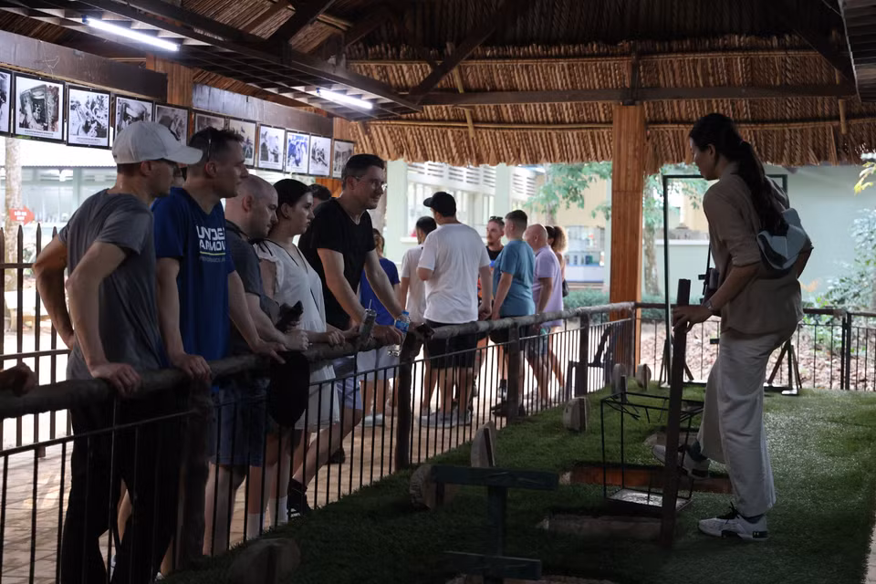 Foreign tourists listen to a guide explaining the role of spike pits in combat. (Photo: VNA)