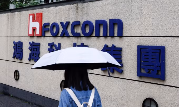 A woman carrying an umbrella walks past the logo of Foxconn outside a company's building in Taipei, Taiwan, Oct. 31, 2022. (Photo: Reuters)