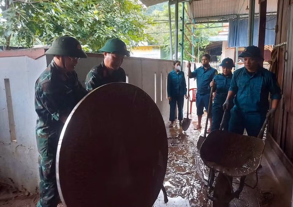 Military personnel help residents clean up and restore the environment following the floods. (Photo: VNA)