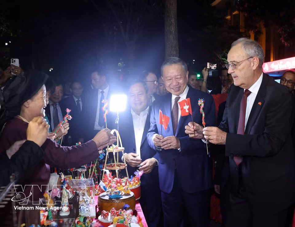 Swiss President Guy Parmelin shows interest in to he, traditional Vietnamese toy figurines made by artisans from Xuan La Village, at the Hoan Kiem Lake pedestrian area. (Photo: Thong Nhat/VNA)