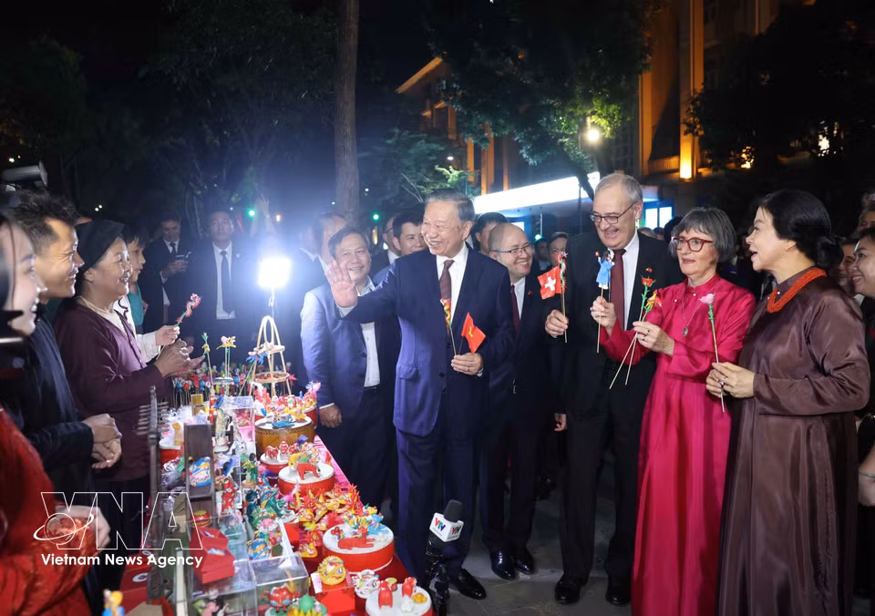 Party General Secretary and State President To Lam and his spouse, Ngo Phuong Ly, join Swiss President Guy Parmelin and his spouse, Caroline Parmelin, in visiting a to he stall run by artisans from Xuan La Village at the Hoan Kiem Lake pedestrian area. (Photo: Thong Nhat/VNA)