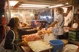 A shopper uses a QR code to make contactless payment to her butcher in Nonthaburi. (Photo: Bangkokpost)
