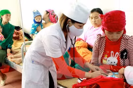 A medical worker examine a child patient (Photo: VNA)