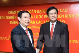 Bouasone Bouphavanh (R) welcomes Vuong Dinh Hue (Photo: VNA)