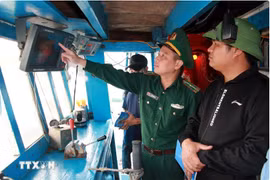 A border guard officer checks monitoring devices on a fishing vessel (Photo: VNA) 