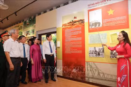 People are told about photo displayed at the exhibition. (Photo: VNA)