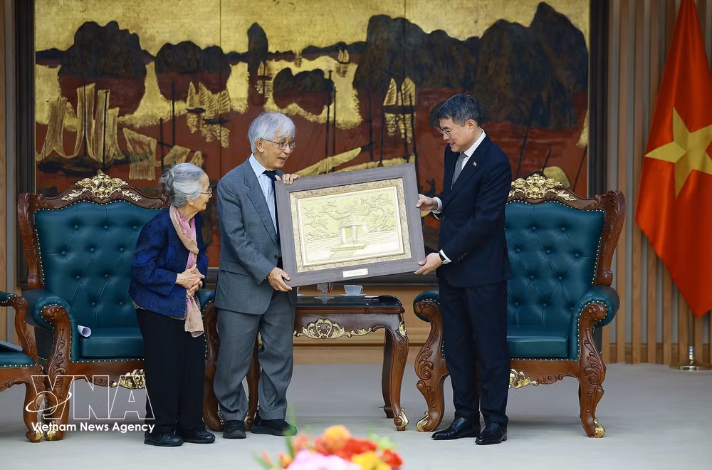 PM Le Minh Hung (R) presents a painting of the Temple of Literature to the two professors at the meeting on August 24. (Photo: VNA)