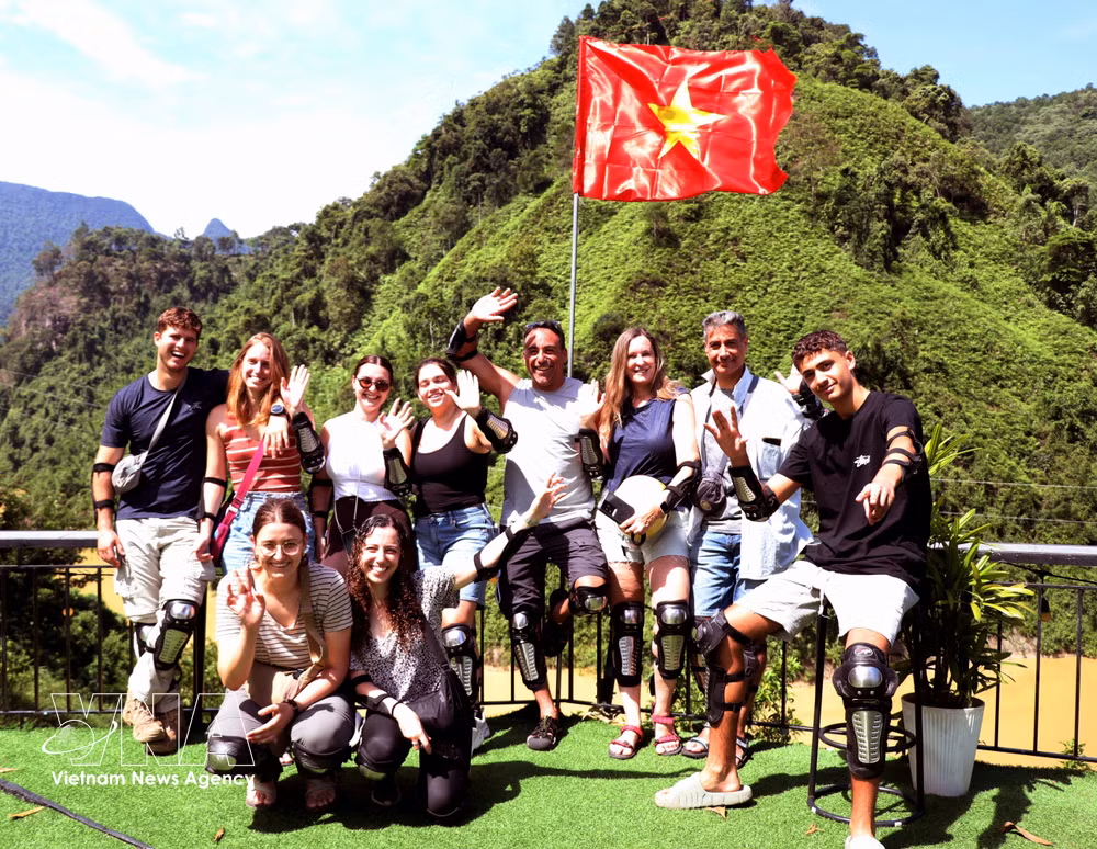 Foreigners take photo besides Vietnam's national flag on the National Day holiday in Tuyen Quang province. (Photo: VNA)