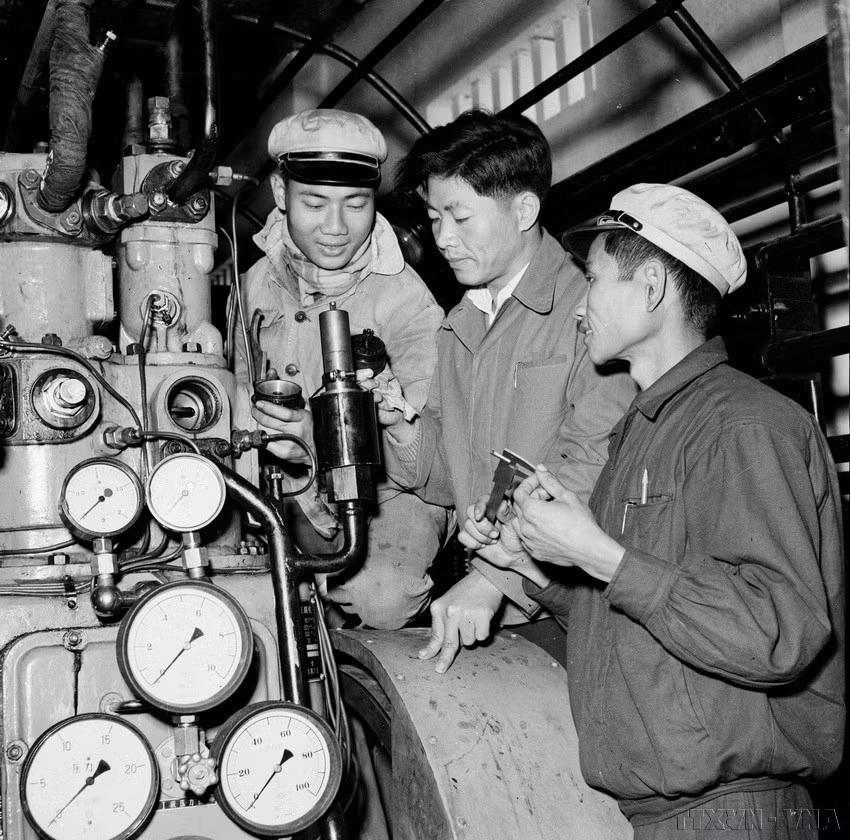 A Chinese expert (center) guides Vietnamese workers in dismantling and repairing an automatic steam release valve at the K65 pressing plant (September 1960). (Photo: VNA)
