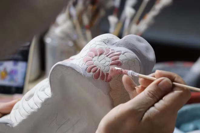 An artisan applies glaze and paints patterns on Bien Hoa pottery at the Phong Son pottery kiln. (Photo: VNA)