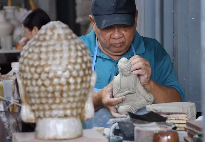 Artisan Le Thanh Nhan, dedicated to Bien Hoa pottery for over 30 years, creates a ceramic Buddha statue. (Photo: VNA)